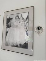 Framed vintage wedding photograph beside wicker heart floral wall hanging