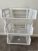 Three white plastic stacking baskets assembled
