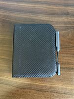 Closed black carbon-fiber textured folio case with stylus attached