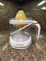 Overall view of Black+Decker electric citrus juicer showing base, container, handle, yellow reamer, lid and cord clip