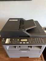 Front and top view of Brother MFC-L2710DW showing scanner lid, control panel and paper tray