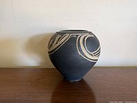 front view of rounded black stoneware vase with beige abstract pattern