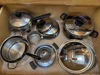 All cookware laid out in drawer: stock pot, saucepans, casserole pot, steamer insert, lids