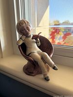 Front view of stoneware figurine showing child reading in textured chair
