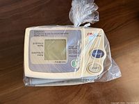 Front view of Omron HEM-711 monitor in plastic bag showing display and controls