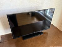 Front view of Samsung flat screen TV on stand with power cord visible