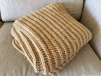 Folded beige chunky-knit throw on sofa