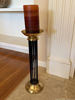 Full view of brass and black Art Deco candle holder with brown pillar candle