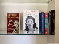 Front view of five biography books on glass shelf
