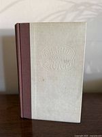 Front view of hardcover showing off-white boards, brown spine, embossed title