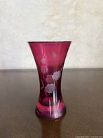 Front view of cranberry glass bud vase showing etched floral design