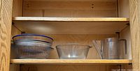 Cabinet shelf with nested glass and metal bowls plus plastic pitcher