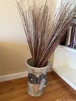 Front view of ceramic umbrella stand showing ram’s head applique and feathers