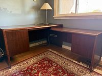 Full view of L-shaped walnut executive desk showing both pedestal bases and rug