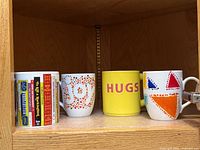 Four mugs on shelf showing designs