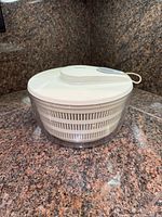 Salad spinner showing full side view with lid on, clear bowl, inner basket visible