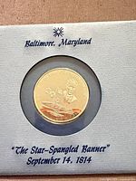 Coin in display card marked Baltimore, Maryland, with title and date