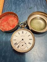 Pocket watch with case opened to show dial and storage components