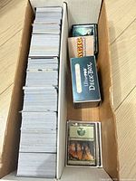 Full storage box showing loose card stack, two deck boxes, and sleeved cards