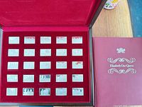 Open display case showing 25 ingots and accompanying book