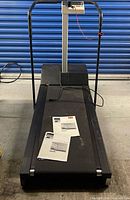 Full view of Precor M9.1 treadmill with manuals on deck