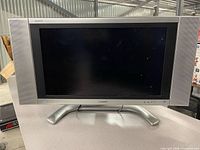 Front view of Sharp AQUOS 26-inch LCD TV with stand and side speakers