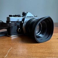 Side view of Olympus OM-1 camera with lens, hood and strap