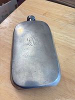 Front view showing monogram and overall wear of pewter flask
