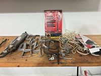 Overall view showing grease gun, C-clamps, hose clamps, band clamp, pulley with rope, jigsaw blade set and timer box