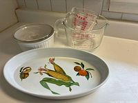 Group view of casserole with lid, three Pyrex cups stacked, Royal Worcester oval dish
