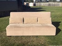 Front view of beige armless sofa with pillows