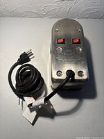 Top view showing metal housing, dual red switches, cord and plug
