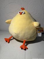 Front view of yellow cartoon chick plush with tag attached showing overall condition and design