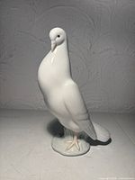 Front/side view of white porcelain dove figurine on base