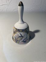 Front view of porcelain hand bell showing peacock floral motif, gold accents, overall condition