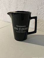 Front view of black Seagram's 100 Pipers ceramic pitcher