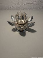 Front view of silver plated lotus votive holder with glass insert