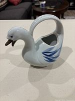 Left side view of swan pitcher showing handle, spout and painted wing