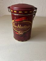 Front of cylindrical Tim Hortons red tin with 40th Anniversary logo and latch lid