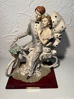 Front view of figurine showing couple, bicycle, attire detail and base