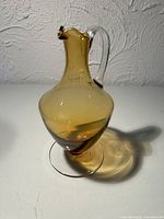 Front view of amber glass ewer showing clear handle and pedestal base