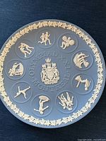 Full view of blue jasperware plate showing relief sports motifs and inscription