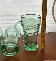 Two glasses upright and one on side with ruler showing height