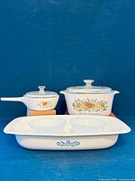 Group view of all cookware pieces including roaster, casserole with lid, saucepan with lid, range topper skillet with lid and two soup bowls