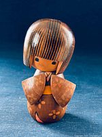 front view of Tomio Ishida kokeshi doll showing floral kimono motif and missing bow area