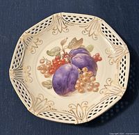 Plate showing plums with currants, detailing reticulated rim and gold accents