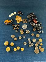 Overview of entire assortment of buttons laid out on blue surface