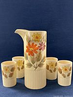 Front view of pitcher with five matching cups showing floral design