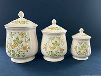 Front view of three canisters with lids showing pattern and relative sizes