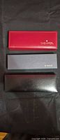 Closed presentation boxes: red Sheaffer, grey Parker, black Lucoral